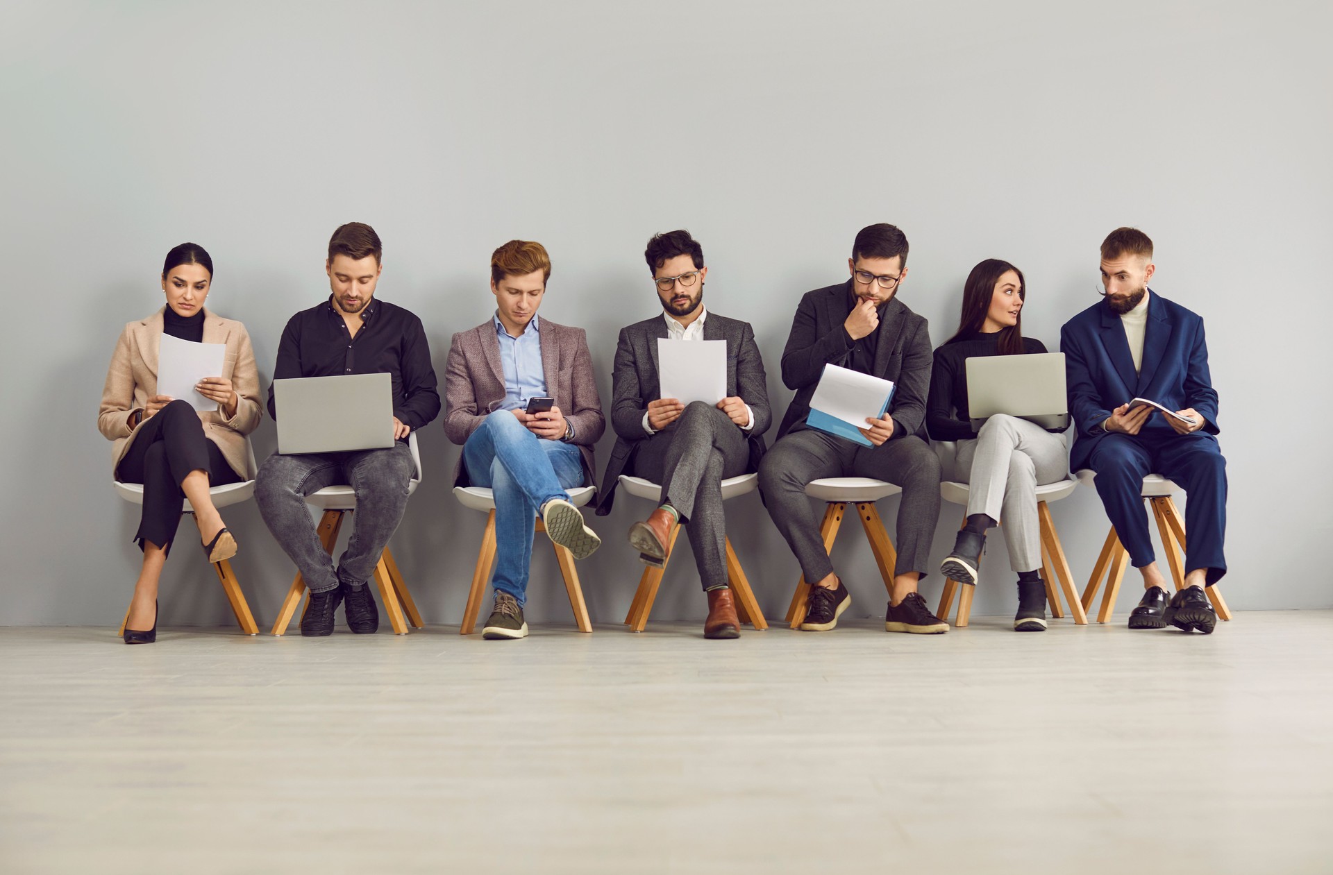 Business people sitting by wall while waiting for their turn to interview